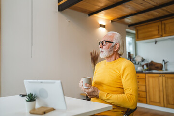 One senior man sit at home in the kitchen with cup of tea or coffee