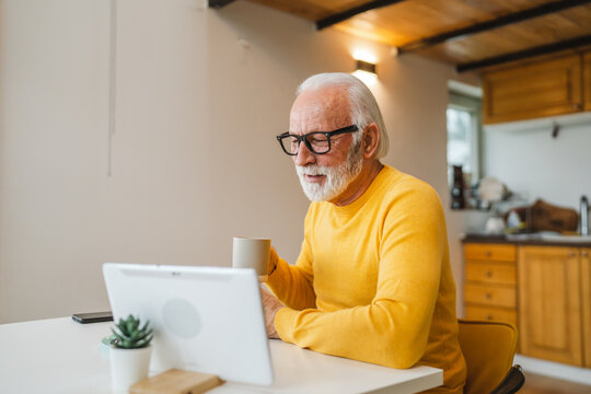 One senior man sit at home in the kitchen with cup of tea or coffee