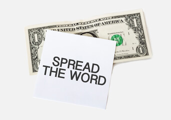 1 dollar bill and white notepad sheet on the white background. Text SPREAD THE WORD