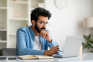 Young Indian Male Writer Working With Laptop At Home Office