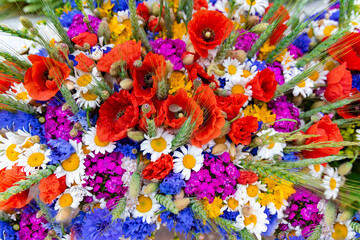 Large bouquet of summer wildflowers with poppies, daisies and cornflowers garnished with wheat ears closeup.  Spring flower background. - obrazy, fototapety, plakaty