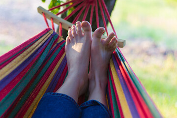 legs on a hammock. outdoor recreation in a hammock. summer vacation. life without gadgets. relaxation from the outside world. good weather and mood. funny toes.
striped hammock.summer landscape.
legs