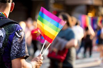 Bandeirolas símbolo do orgulho gay nas mão de vendedores ambulantes na  27ª edição, da Parada do Orgulho LGBT+ de São Paulo, Avenida Paulista, Brasil.  - obrazy, fototapety, plakaty