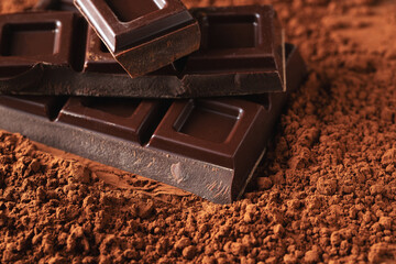 Dark and milk chocolate with nuts on a dark background sprinkled with cocoa powder.