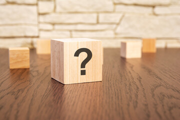 wooden blocks with question sign on wooden table, close up. space for text
