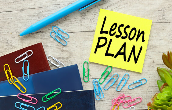 Lesson Plan yellow sticker with text on desktop. a lot of scattered paper clips on the table