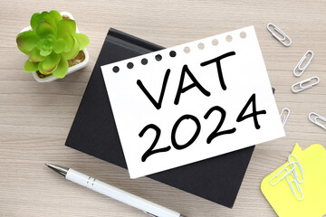 VAT 2024 year economic analysis concept. white pen. text on torn paper. plant in the pot.
