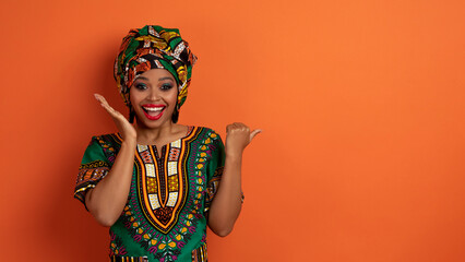 Excited young black woman in african costume showing nice offer