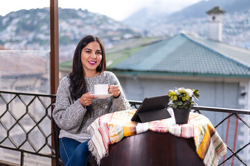 latina girl smiling and drinking coffee at a rooftop restaurant