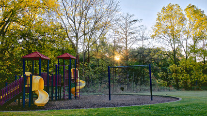 Sunrise in the public park with Slide-play equipment in the playground.