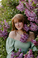 Young woman standing in the purple lilac bush.