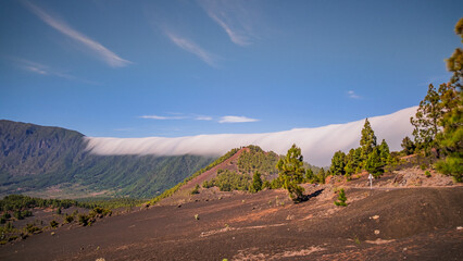 Clouds move over the mountain slope of Cumbre Nueva and flow into the valley like a waterfall, La Palma, Canary, Spain, Europe