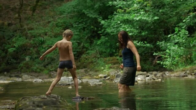 Mother and her boy child in forest stream. Creative. Hiking in wild jungles on a summer day.