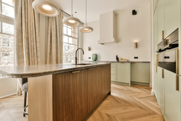 a kitchen with wood flooring and light green cabinets in the center of the room is a large window...