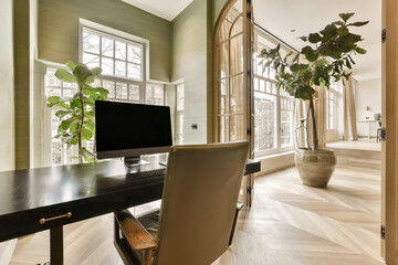 a home office with a desk, chair and large window looking out onto the street in front of the house