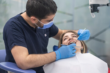 Obraz premium Dental care in modern clinic focused orthodontist looking at teeth of female patient using professional tools skilled specialist preparing woman for bite correction