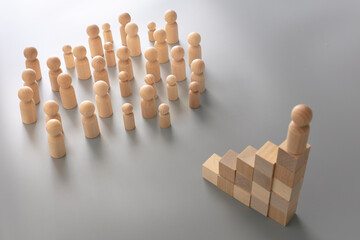 Leader figure standing out from crowd on wooden cubes, other figures in front on floor. Leadership...