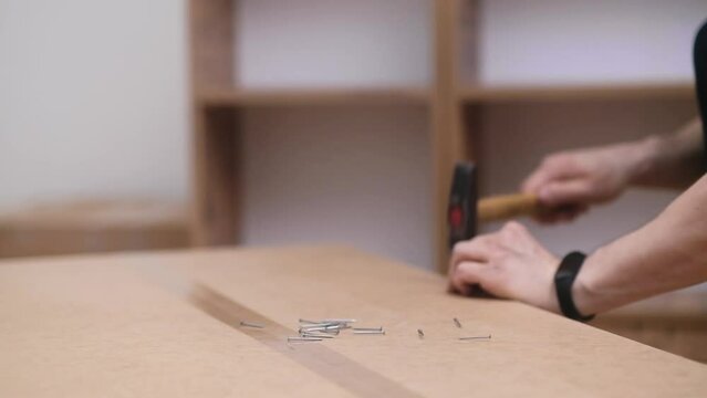 Furniture fixing process handyman hammering tiny nails into back of wooden cabinet designed for office interior firm worker uses professional tools carpentry business