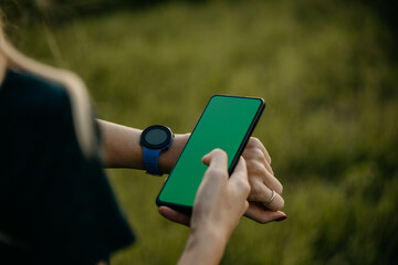 Connected and Active: Against a backdrop of a green hill, a Caucasian jogger harnesses the power of technology, glancing at her smartwatch for insights on speed, distance, and calories burned.