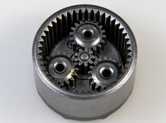 A close-up with a metallic planetary gear set on a white background
