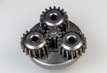A close-up with a metallic planetary gear set on a white background