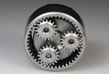 A close-up with metallic planetary gear set on a white background. It is a speed reduction gear