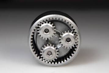 A close-up with a metallic planetary gear set on a white background