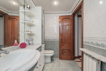 Conventional toilet with white and green wooden furniture with porcelain sink embedded