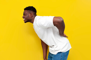 african american man in white t-shirt holding on to his back and bending over yellow isolated...