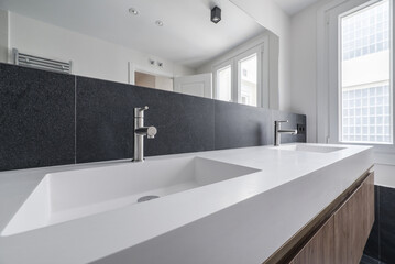 Image of a beautiful contemporary bathroom with a long double sink, huge frameless mirror