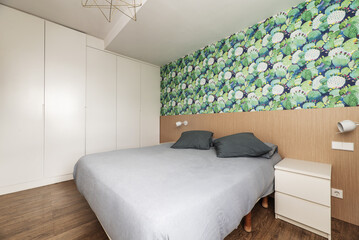 Double bedroom with a large bed with papered walls