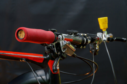 Bleeding the brake system of a mountain bike with a funnel. Bicycle repair. A mountain bike handlebar and modern disc hydraulic brakes on a black background.