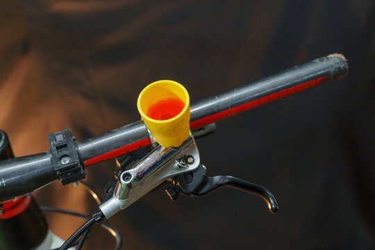 Bleeding the brake system of a mountain bike with a funnel. Bicycle repair. A mountain bike handlebar and modern disc hydraulic brakes on a black background.