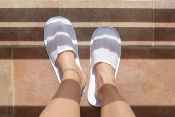 Feet in white hotel slippers on balcony
