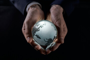 A man holds a glowing globe in his hands. close-up on a black background