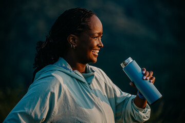 Natural hydration: Highlight the benefits of natural hydration by capturing a woman in sports attire drinking water from a bottle against nature.