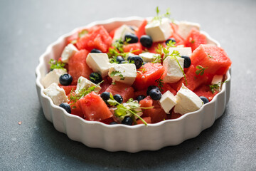 Summer salad with watermelon, feta cheese and mint on a gray background. Vegan, European food.