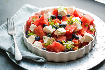 Summer salad with watermelon, feta cheese and mint on a gray background. Vegan, European food.