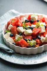 Summer salad with watermelon, feta cheese and mint on a gray background. Vegan, European food.