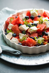 Summer salad with watermelon, feta cheese and mint on a gray background. Vegan, European food.