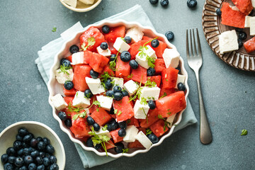 Summer salad with watermelon, feta cheese and blueberry on a gray background. Vegan, European food.