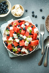 Summer salad with watermelon, feta cheese and blueberry on a gray background. Vegan, European food.