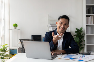 Asian businessman writing financial graph chart marketing information plan Male hand using laptop at desk reading financial document spreadsheet for calculation and analysis.