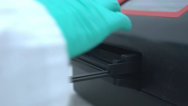 Automatic opening of the microplate reader, and scientist picking up the the microtiter plate. 