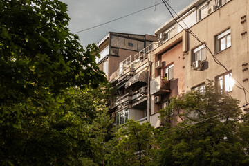 Selective blur on a facade of a decaying residential multistorey building, with old grey facade, at sunset, in the city center of Belgrade, Stari Grad, in Dorcol district.