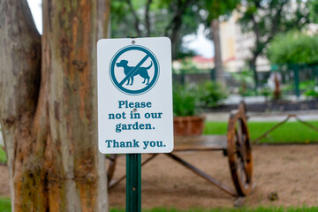 No Dogs Allowed green and white sign in a city garden