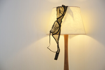 Woman's black lace bra on the lamp in the hotel room - obrazy, fototapety, plakaty