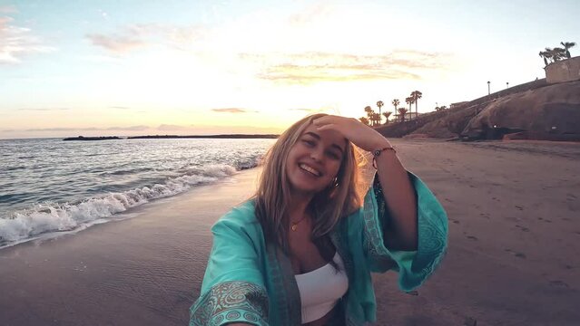 One blonde caucasian young beautiful woman running and looking at the camera taking a selfie at the beach enjoying summer time outdoor on holiday. 