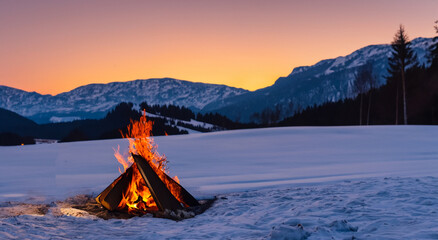beautiful flaming campfire in the middle of the snow with a beautiful sunset in high definition and...