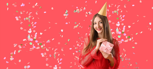 Obraz na płótnie Canvas Happy young woman with Birthday gift and falling confetti on red background. Banner for design